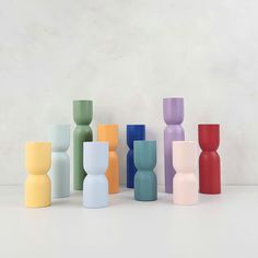 several different colored vases are lined up in a row on the floor, with one standing out from the others