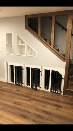 an empty living room with dog doors on the wall and stairs to the second floor