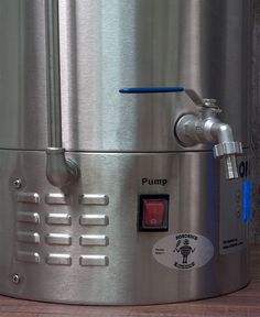 a stainless steel water heater sitting on top of a wooden table