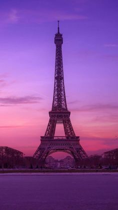 the eiffel tower is lit up in purple and pink colors as the sun sets