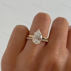 a woman's hand with a diamond ring on top of her finger and an engagement band