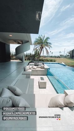 a couch sitting next to a swimming pool in front of a large building with palm trees