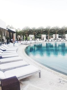 lounge chairs line the edge of an empty swimming pool