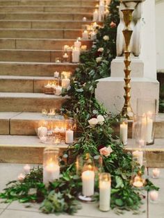 candles are lined up on the steps with greenery