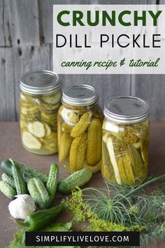 pickles and cucumbers are in jars with herbs on the table next to them