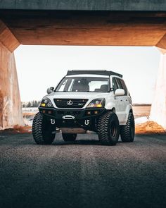 a white four door suv parked under a bridge