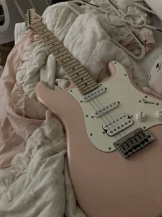 a pink guitar laying on top of a bed