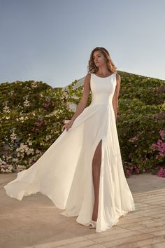 a woman in a long white dress posing for the camera