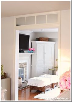 a living room with white furniture and pink flowers on the fireplace mantels in front of it