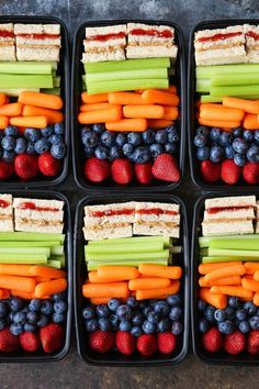 six trays filled with different types of food including carrots, celery and strawberries