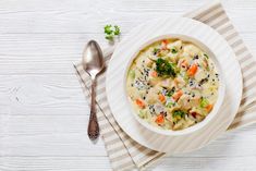 a bowl of soup with broccoli, carrots and cauliflower on a striped napkin