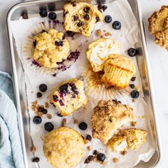 muffins with blueberries and crumbs are on a baking sheet, ready to be eaten