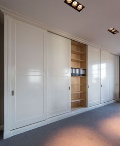 an empty room with white cupboards and bookshelves