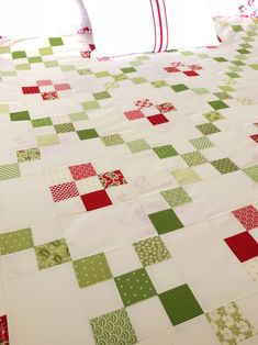 a quilted table runner with red, green and white squares on the bottom half