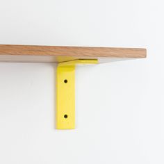 there is a yellow object on the wall next to a wooden shelf that has two holes in it