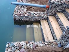 some kind of dock made out of wood and rocks with a pipe sticking out of it