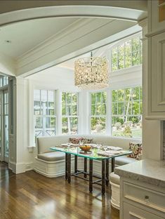 a dining room table and bench in front of large windows