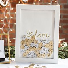 a table topped with lots of gold and white confetti next to a sign