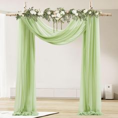 a green drape with white flowers and greenery on it in an empty room