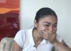 a woman covers her mouth while sitting on a couch