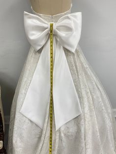 Add a touch of elegance to your special day with our unique handmade large size wedding dress bow. This stunning bridal bow is meticulously crafted with love and care in Florida, ensuring the highest quality. Made to accentuate your wedding dress, this bow adds a beautiful finishing touch to your bridal ensemble. Our large size wedding dress bow is designed to make a statement. Its intricate detailing and exquisite craftsmanship make it a truly one-of-a-kind accessory. Whether you're going for a Elegant Wedding Sashes With Decorative Bow, Elegant Satin Bow Tie For Wedding, Fitted Wedding Sashes With Bow, White Satin Bow Tie For Wedding, Elegant White Bow Tie For Wedding, White Detachable Bow Tie For Wedding, White Satin Bow Sash For Wedding, White Satin Bow Sashes For Wedding, Fitted Wedding Bow Tie With Tie Back