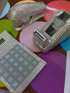 a cell phone and some kind of silver case on a table with circles around it