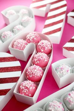 valentine's day desserts in heart shaped boxes on a pink table with red and white stripes