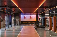 an indoor gym with rows of exercise mats and punching bags on the floor, surrounded by orange lights