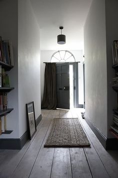 an empty hallway with bookshelves and a rug on the floor in front of it