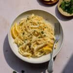 a white plate topped with pasta next to bread