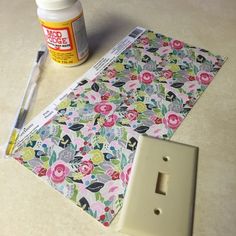 a light switch cover sitting on top of a table next to a bottle of glue