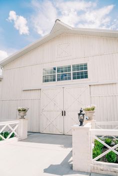 a large white barn with two doors and windows