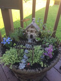 a potted planter filled with plants and a birdhouse on top of it