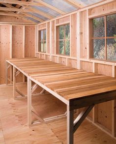 an empty room with wooden walls and windows in the center is being built on top of wood planks