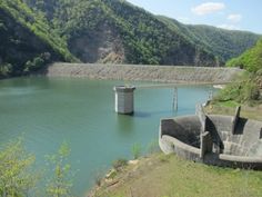 a large body of water surrounded by hills and trees on the side of a hill