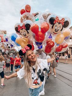 a woman holding mickey mouse balloons in her hands