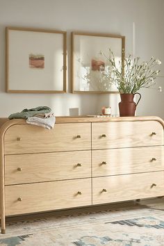 a large wooden dresser sitting next to two framed pictures