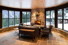 a living room filled with lots of furniture next to large windows and a stone fireplace