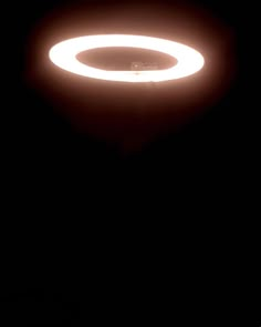 a black and white photo of a light in the dark with an orange ring around it