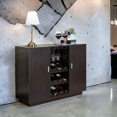 a wooden cabinet with wine glasses and bottles in it next to a lamp on a table