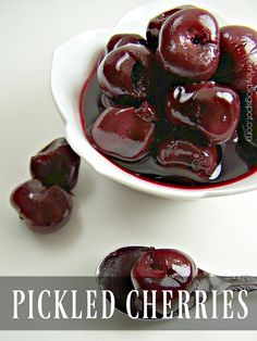 a white bowl filled with cherries on top of a table next to a spoon