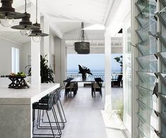 an open kitchen and dining room area with white walls, floor to ceiling windows, and lots of light