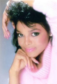 a woman in pink sweater posing with her hand on her head