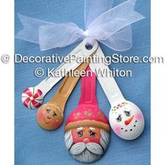 three wooden spoons with painted faces and bows on them are hanging from a ribbon