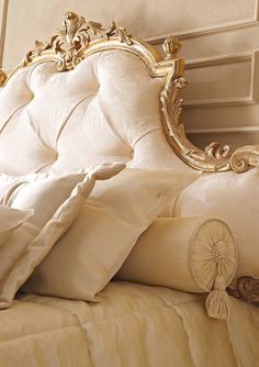 a white bed with gold trim and pillows