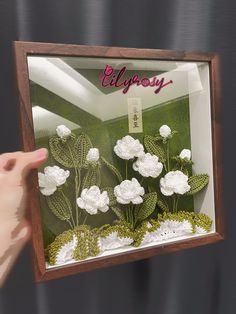 a hand is holding up a glass display case with flowers in it and the words ellipossy written on it