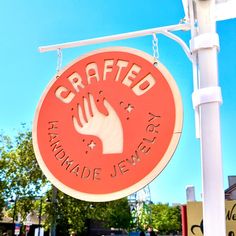 a sign that says crafted handmade jewelry hanging from a light pole in front of a building