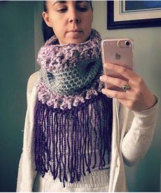 a woman taking a selfie with her cell phone wearing a crocheted scarf