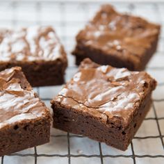 four brownies on a cooling rack with frosting in the middle and one is cut into squares