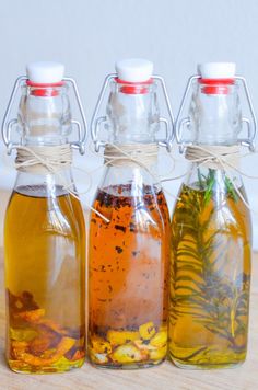 three bottles filled with different types of liquid on top of a wooden table next to each other